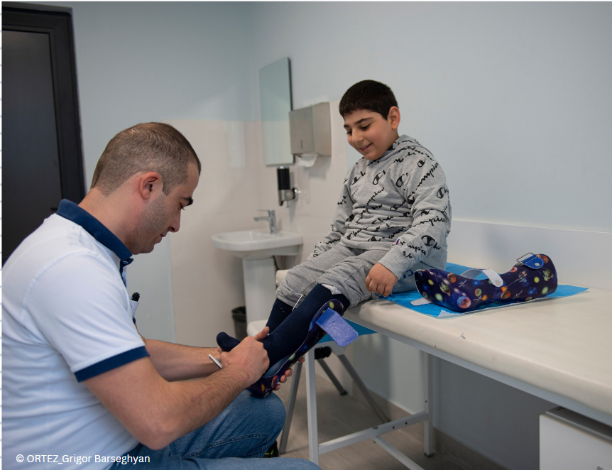An orthotist is fitting an ankle foot orthosis to a young boy.